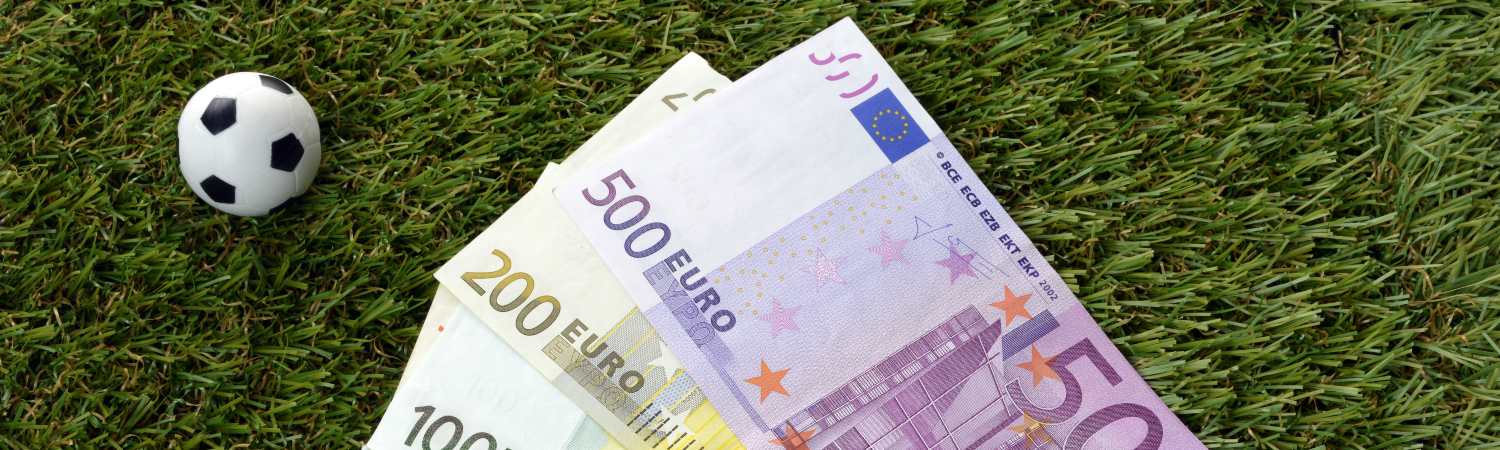 cancha con balón y dinero con Over 2.5 en las apuestas deportivas