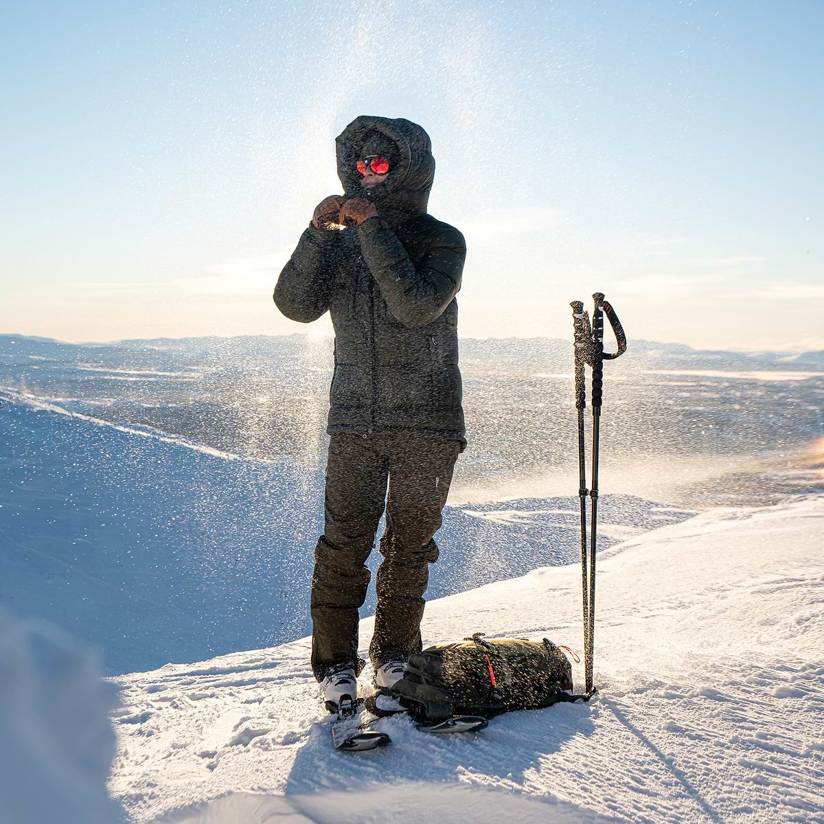 A female backcountry skier just reached a summit, getting ready to drop in, in Åre, Sweden. Wearing the Stellar Eq Red Hot Down Parka in dark green.