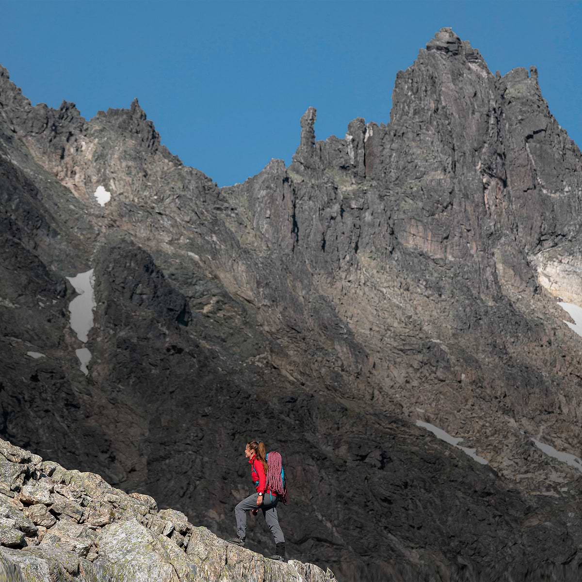 A woman walking on a ridge on her way to the top of a mountain in Kvanndalstind, Norway. Wearing the Stellar Eq W Softshell Pants in dark grey.