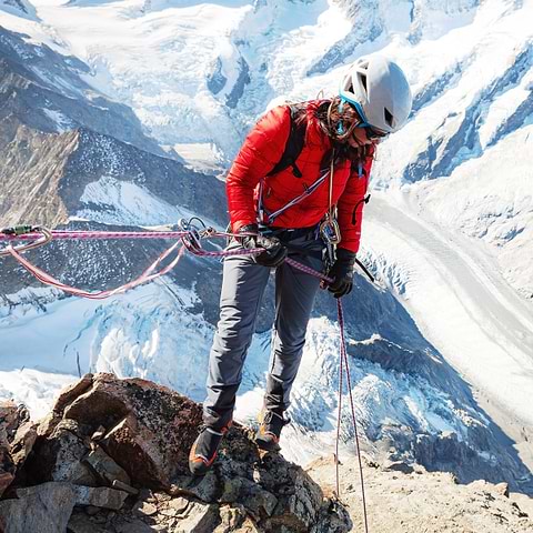 A female climber rappelling down a cliff in Schreckhorn, Switzerland. Wearing the Stelar Equipment Softshell Pants in grey.