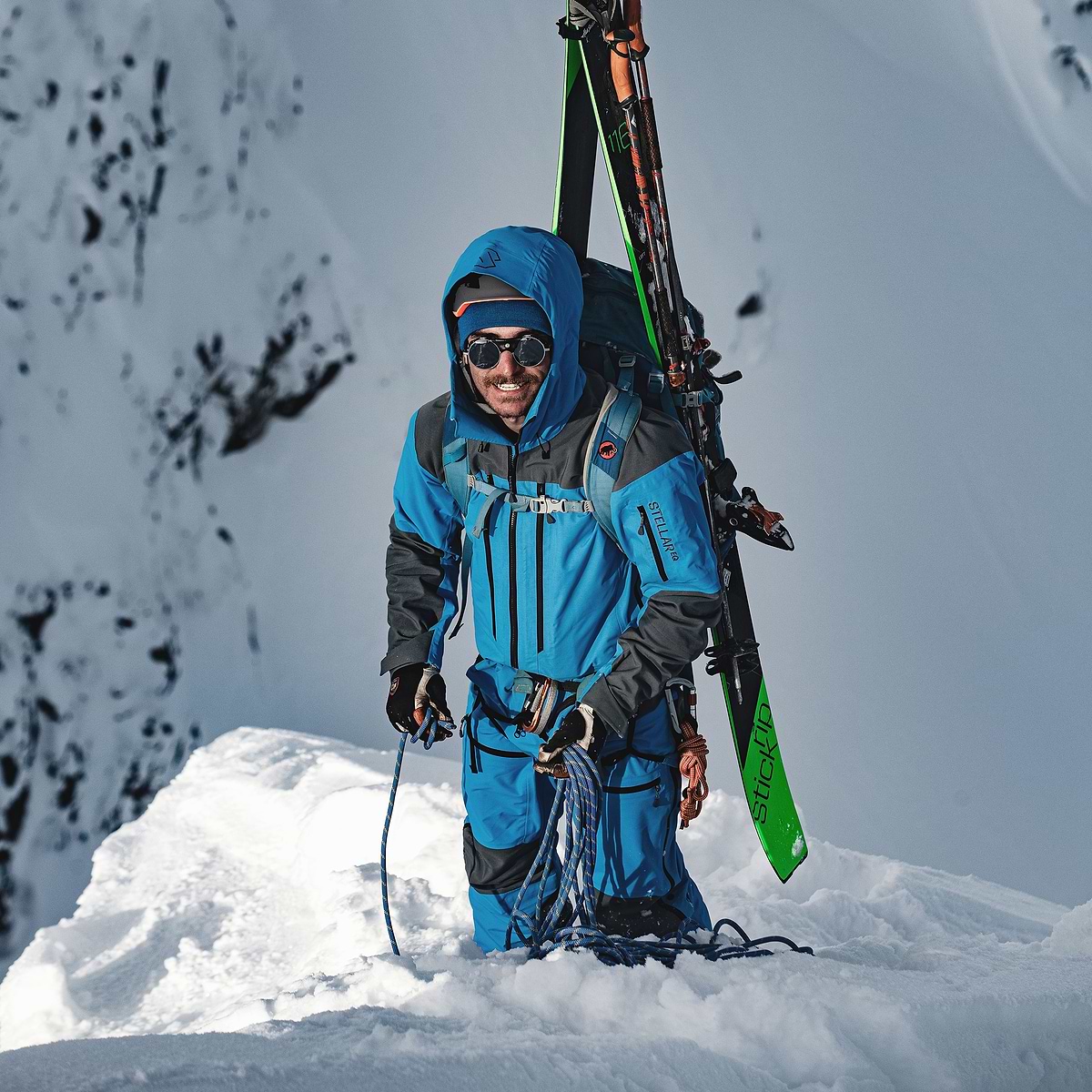 Adrien Grabinski standing on a sunny mountain top in Terrace, Canada wearing the Stellar Equipment Mens Guide Shell 2.0 System in Blue.