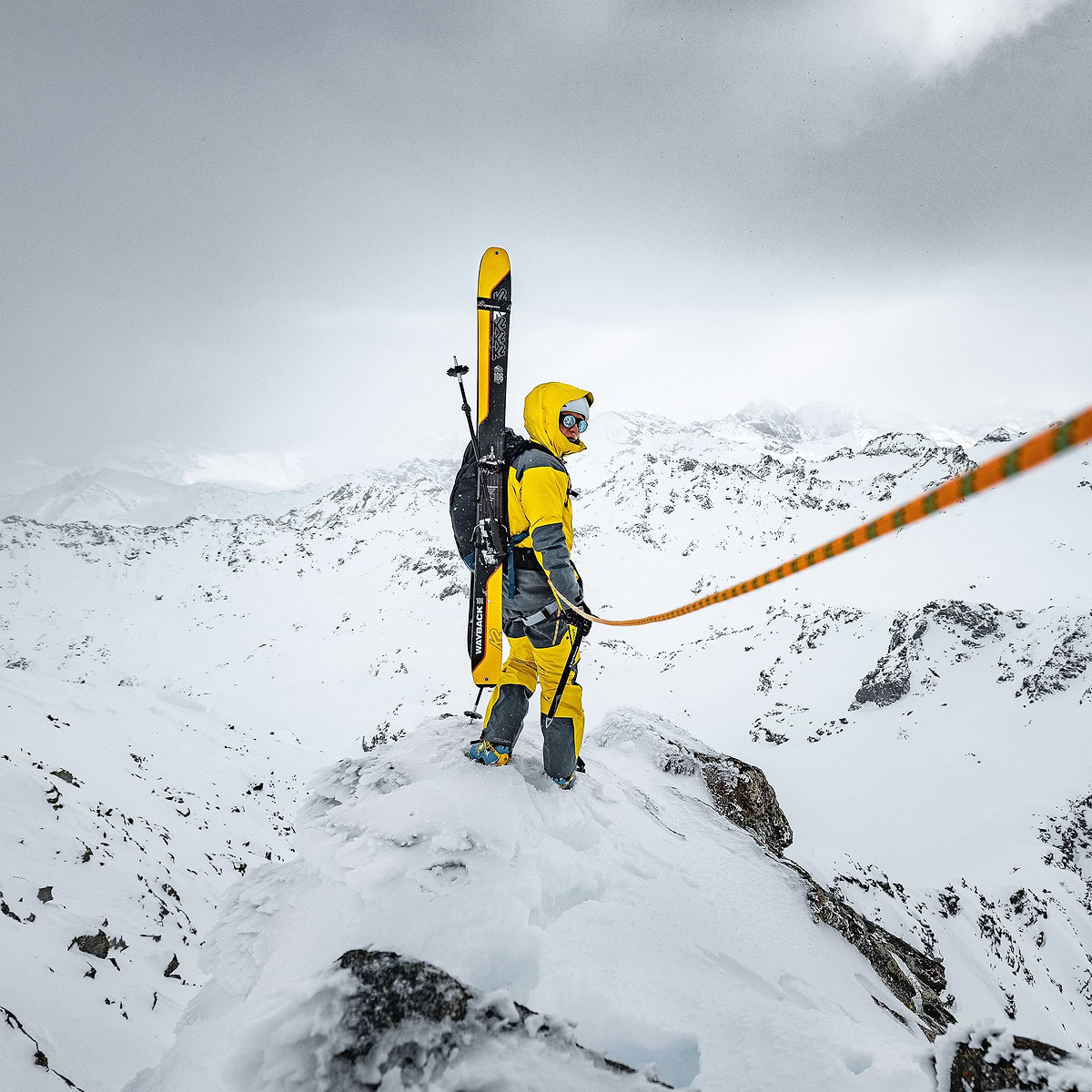 Baptiste Sjöström climbing a ridge in Verbier, Switzerland. He is wearing the full Stellar Equipment mens Guide Shell 2.0 System in yellow.
