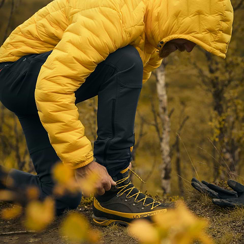 David Kantermo tying his shoes in Björkliden, Sweden. Wearing the Stellar Equipment Softshell Pants 2.0 in Dark Grey.