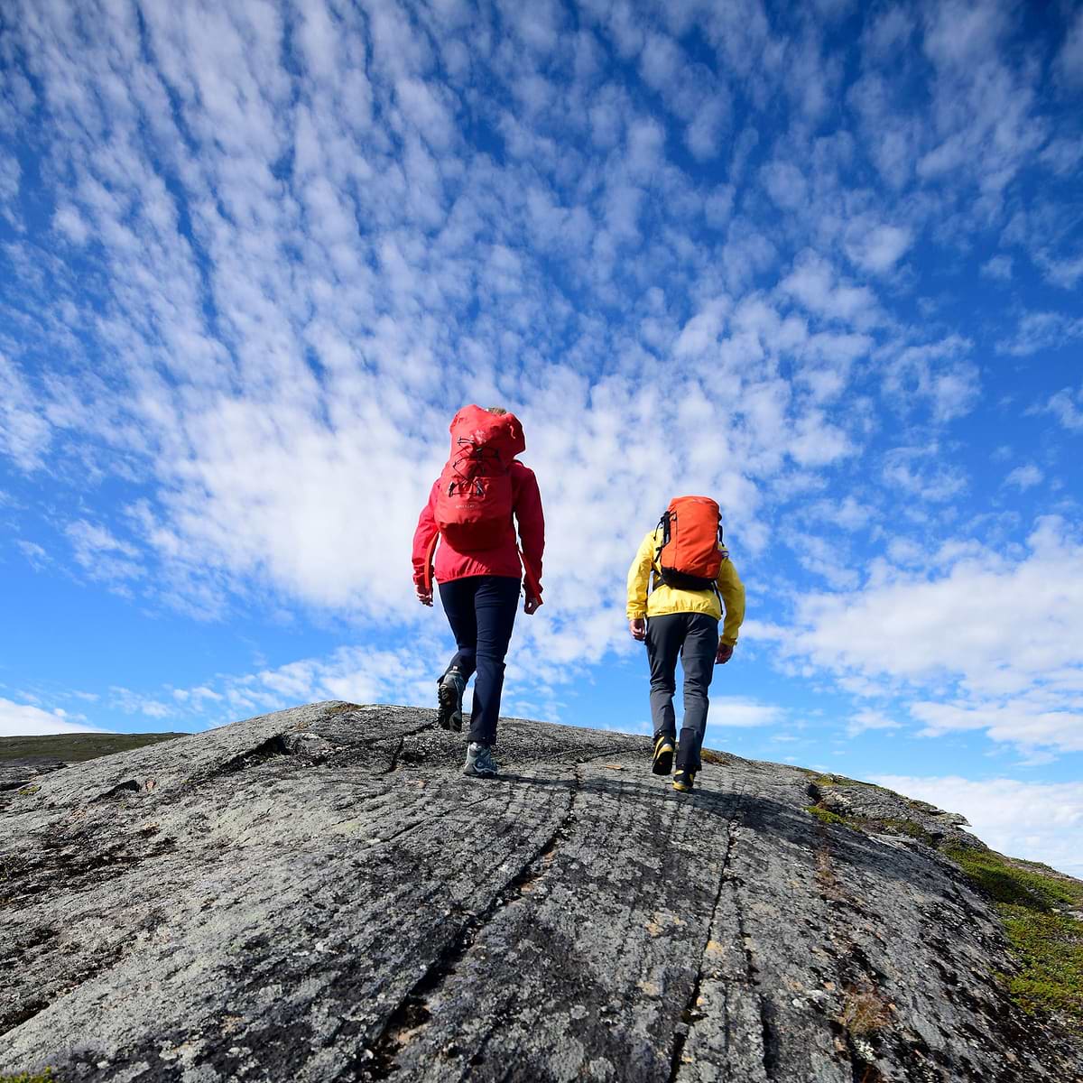 Two hikers aiming for the summit on a mountain. Both of them are wearing the Stellar Equipment Softshell pants in grey.