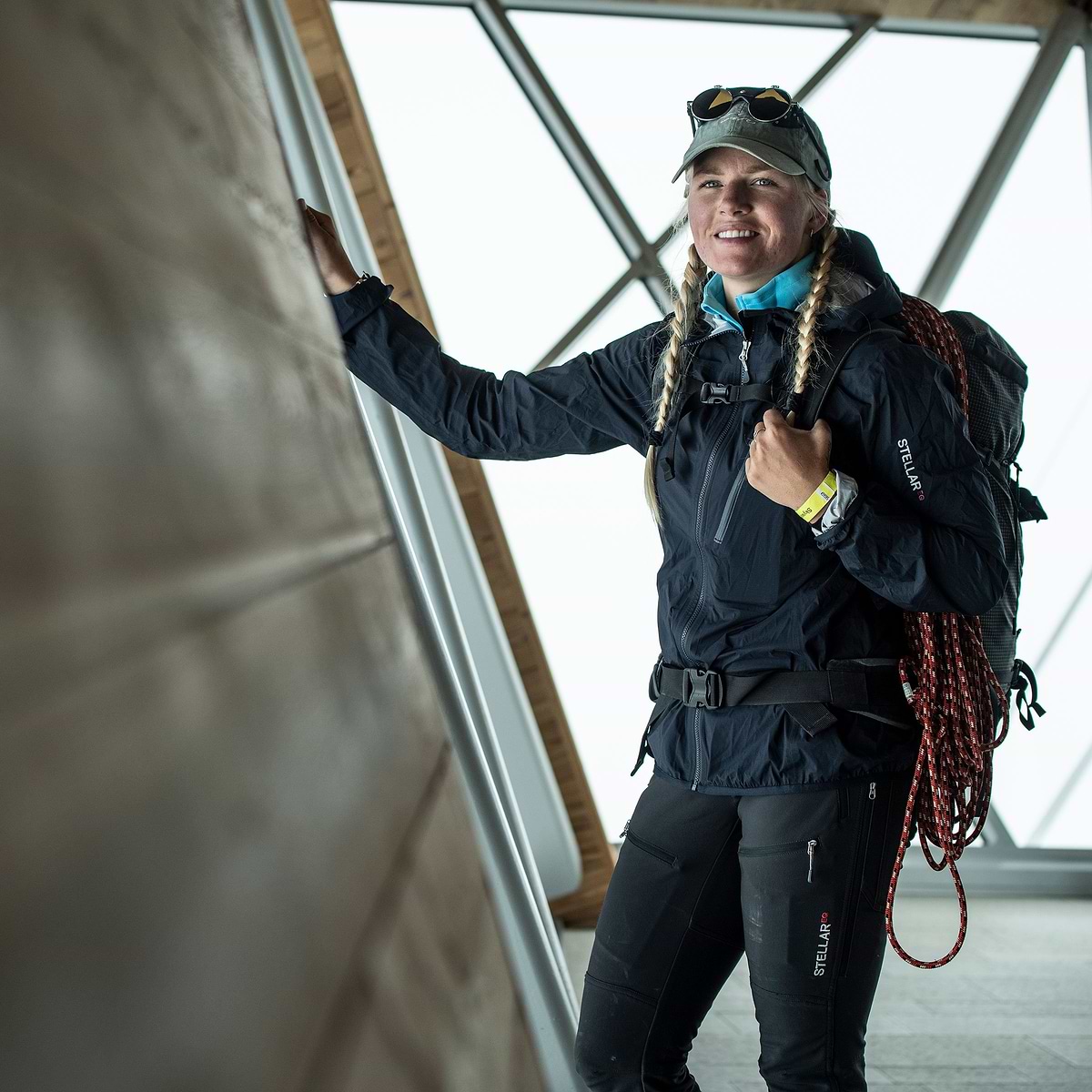 A woman preparing to hike on the mountain, wearing the Stellar Equipment Ultralight Shell Jacket in Dark blue.