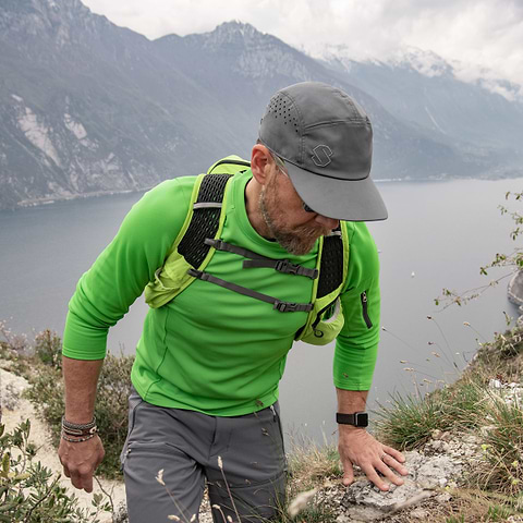 A hiker is out exploring the mountains. Wearing the Stellar Equipment Light Mid Sweater in green.