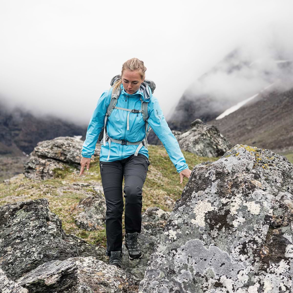A female hiker is walking in a valley in Björkliden, Sweden. Wearing the Stellar Equipment Softshell Pants in Grey.