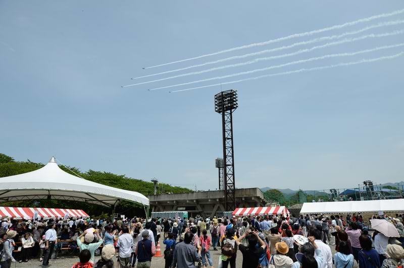 ブルーインパルスもアクロバット飛行で盛り上げに一役。 カメラに収めようと見上げる来場者ら