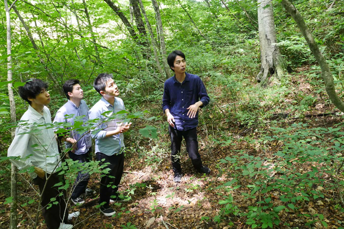 矢野建築設計事務所のメンバーを森に案内するヒダクマの松本氏（右）